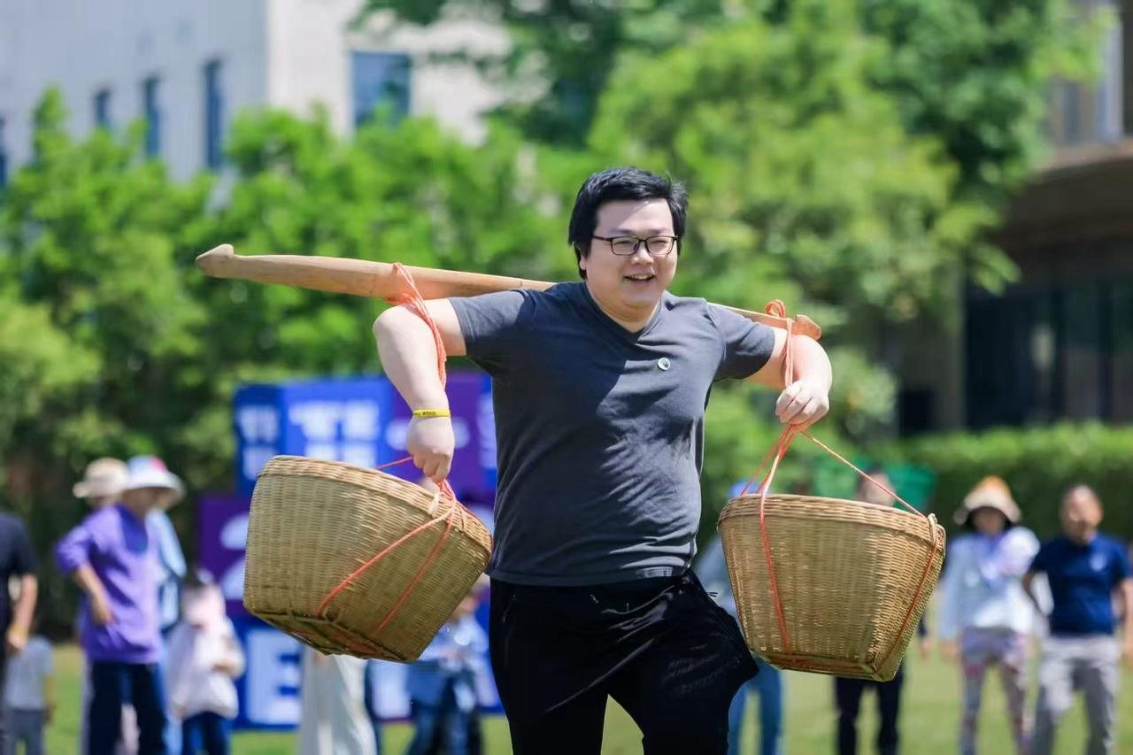 Azhe back then: racing with a carrying pole and baskets at a company field day, grinning