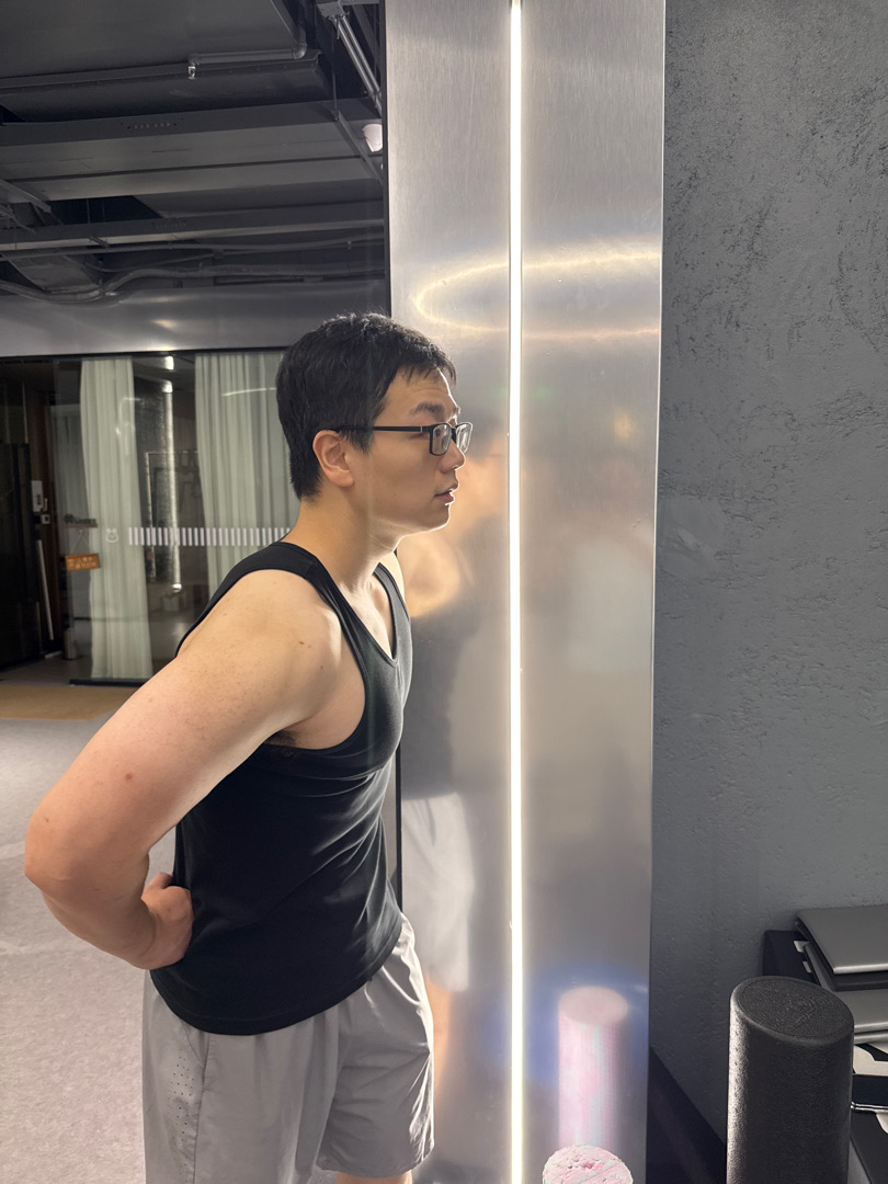 Azhe in profile at the gym mirror, six months on